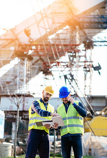 Two construction workers reviewing a plan with numerous tools around them.